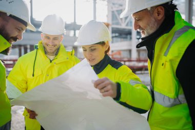 Mühendisler ve inşaat işçileri modern inşaat alanındaki gelişmeleri inceliyor..