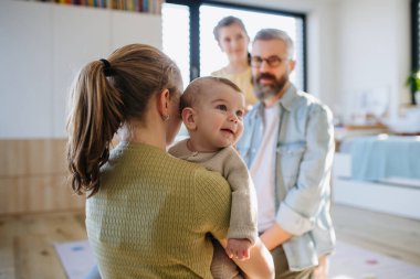 Büyük abla küçük erkek kardeşini kollarında tutuyor, ona bakıyor..