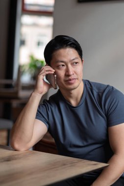 Kafe masasında kendine güveni tam bir delikanlının telefonu var..