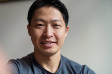 Kameraya bakıp gülümseyen yakışıklı Asyalı bir adamın portresi..