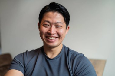 Kameraya bakıp gülümseyen yakışıklı Asyalı bir adamın portresi..