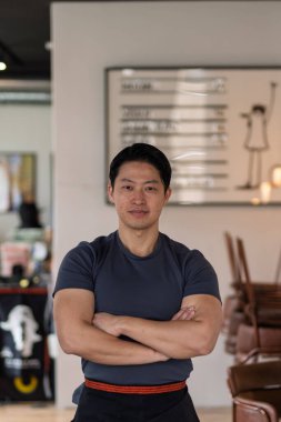 Atletik Asyalı adam sıradan bir ortamda, gülümsüyor..