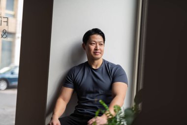 Kendinden emin genç adam pencerenin kenarında oturuyor, dinleniyor..