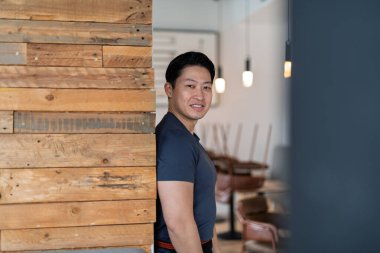 Atletik Asyalı adam sıradan bir ortamda, gülümsüyor..