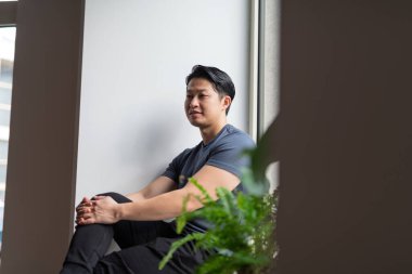 Kendinden emin genç adam pencerenin kenarında oturuyor, dinleniyor..