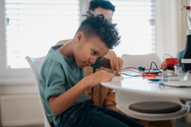 Genç okul çocuğu robot malzemeleri monte ediyor ve evde devre kartıyla çalışıyor..