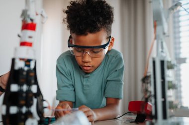 BTMM eğitiminin bir parçası olarak evde küçük bir robot oyuncağı üzerinde çalışan odaklanmış çocuk.