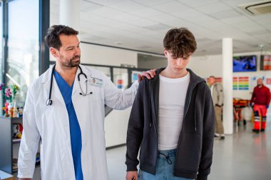 Şefkatli doktor, genç hastayı doktor muayenehanesinde rahatlatıyor..