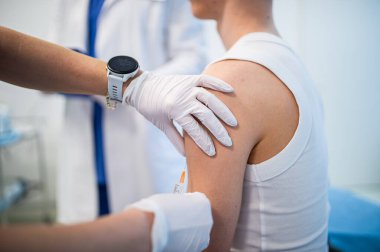 Genç çocuk klinikte rutin sağlık kontrolü sırasında aşı oluyor..