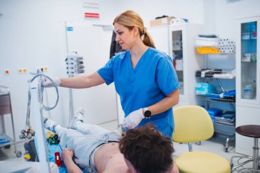 Genç hasta üzerinde yapılan kalp testinden sonra EKG elektrotlarını çıkaran hemşire..