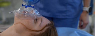 Hastane personeli, hastanedeki baygın genç kıza oksijen maskesi takıyor. Kopyalama alanı olan pankart.