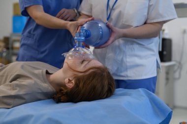 Hastane personeli, hastanedeki baygın genç kıza oksijen maskesi takıyor. Tıbbi prosedür.