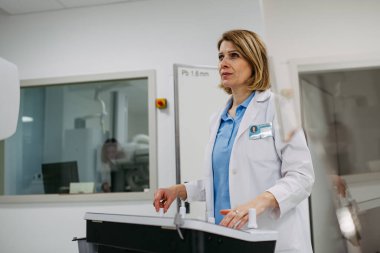 Kadın doktor floroskopi ünitesi kullanarak dinamik röntgen taraması yapıyor.