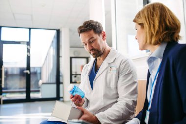 Kadın tıbbi satış temsilcisi doktorlara ilaç ürünlerini tanıtıyor. Hastane ayarları.