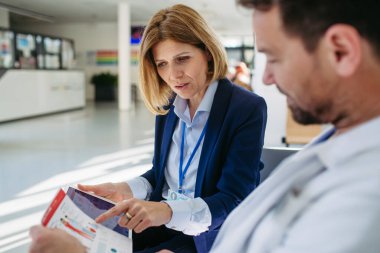 İlaç mümessili ve doktor ilaç örnekleri ve reçeteleri tartışıyor, hastane bekleme odasında oturuyor..