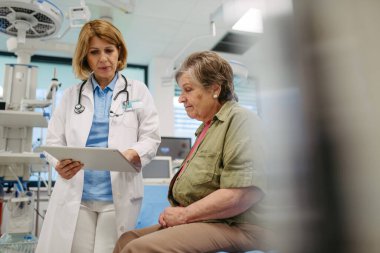 Geriatrist, muayene sırasında yaşlı bir hastayla test sonuçları hakkında konuşuyor. Tıbbi danışma.