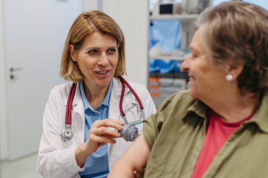 Yaşlı hastaların koluna CGM sensörü takan kadın doktor. Tıbbi ayar.