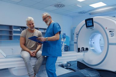 Doktor tomografi sonuçlarını hastane ortamındaki erkek hastaya açıklıyor.