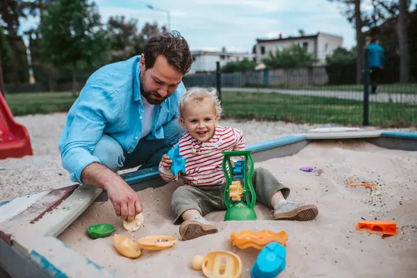 Baba ve küçük çocuk oyun parkında oynuyorlar, hafta sonu eğlencesi..