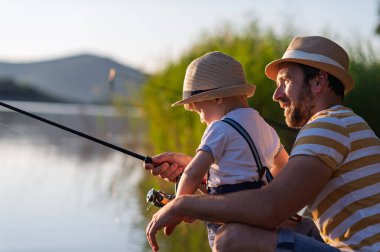Babası küçük oğluna gölde balık tutmayı öğretiyor.