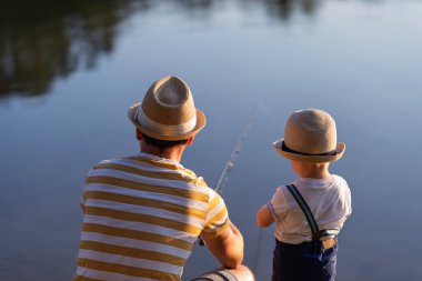 Babası küçük oğluna gölde balık tutmayı öğretiyor.