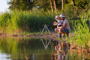 Babası küçük oğluna gölde balık tutmayı öğretiyor.