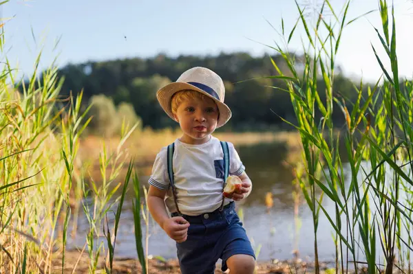 Lastik botlarla gölün sığ sularında yürüyen bir çocuk. Boşluğu kopyala.