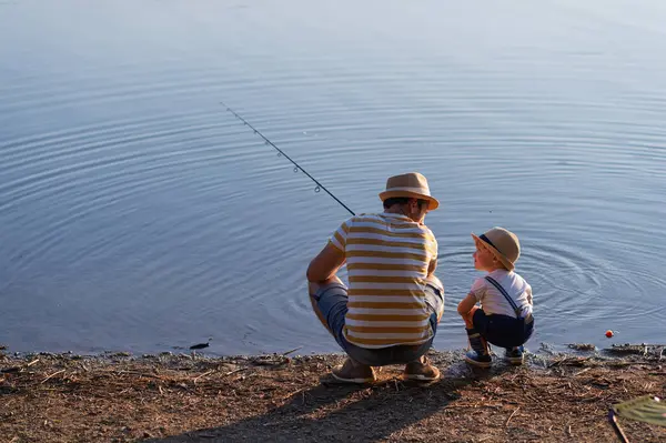 Babası küçük oğluna gölde balık tutmayı öğretiyor.