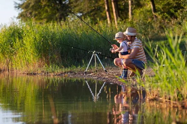 Babası küçük oğluna gölde balık tutmayı öğretiyor.
