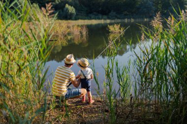 Babasının ve küçük oğlunun, elinde olta tutarken, gölün kenarında dikiz aynasından.
