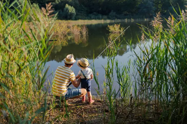 Babasının ve küçük oğlunun, elinde olta tutarken, gölün kenarında dikiz aynasından.