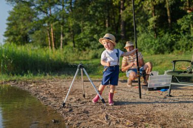 Babası küçük oğluna gölde balık tutmayı öğretiyor.