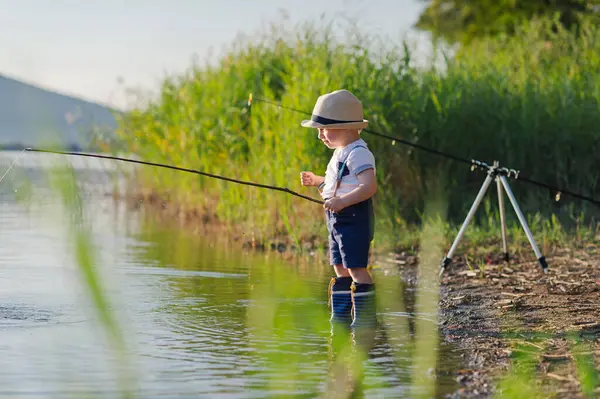 Göl kıyısında balık tutan küçük çocuğun yan görüntüsü. Boşluğu kopyala.