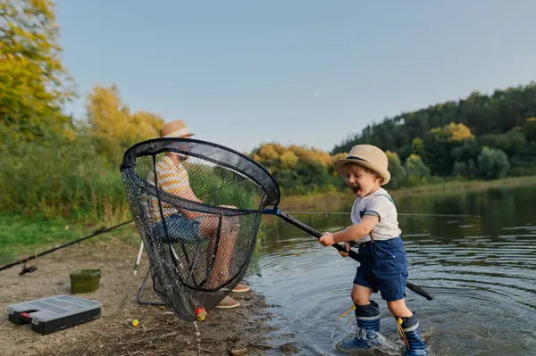 Ufaklık göl kıyısındaki balık ağları için babama yardım ediyor. Babalar gününde balık tutma gezisi.