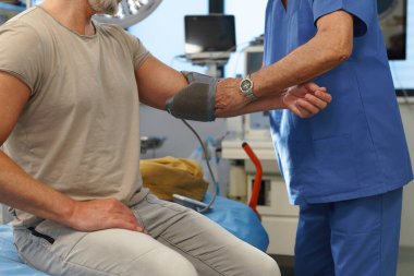 Doktor hastaların tansiyonunu dijital tansiyon monitörü kullanarak ölçüyor..