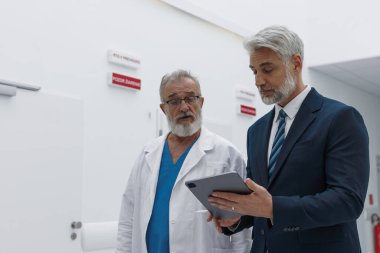 Doktor hastane müdürüyle konuşuyor, ona belgeleri gösteriyor..