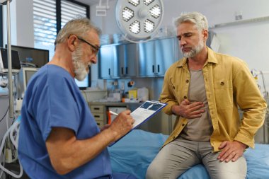 Hasta sağlık sorunlarını yaşlı doktora anlatıyor. Tıbbi muayene.