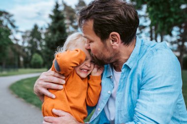 Baba, parkta duygusal bir an yaşarken oğlunu teselli ediyor.