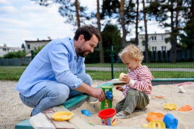 Baba ve küçük çocuk oyun parkında oynuyorlar, hafta sonu eğlencesi..