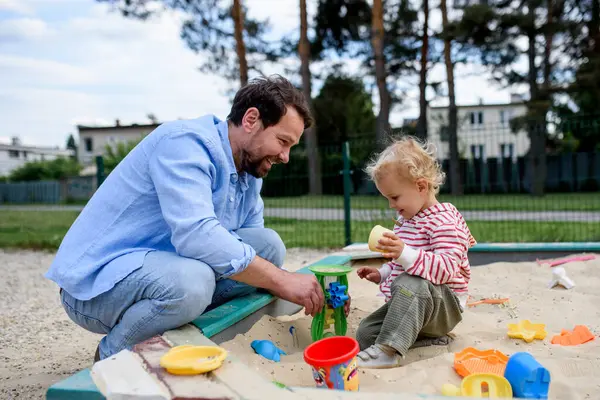Baba ve küçük çocuk oyun parkında oynuyorlar, hafta sonu eğlencesi..