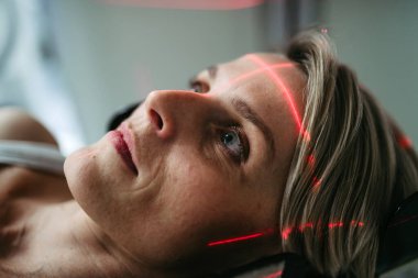 Hasta beyin taraması için bilgisayarlı tomografiye yerleştirildi. Kırmızı lazer çizgileri.