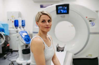 Tomografi yatağında oturan endişeli kadın muayeneyi bekliyor.