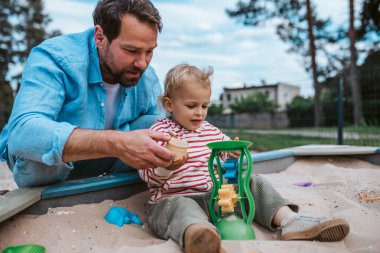 Baba ve küçük çocuk oyun parkında oynuyorlar, hafta sonu eğlencesi..