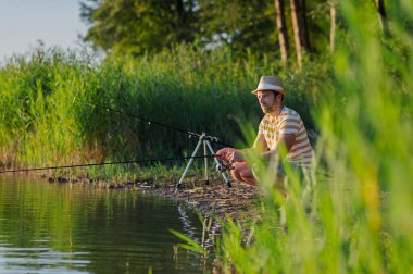 Gün batımında gölde balık tutan bir adam. Arka görünüm.