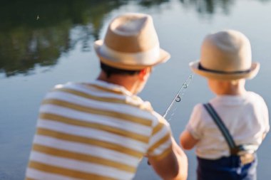 Babası küçük oğluna gölde balık tutmayı öğretiyor.