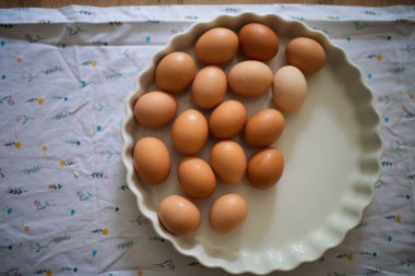 Porselen kasede taze kahverengi yumurtalar. Ahşap mutfak masasında taze çiftlik yumurtaları.