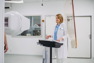 Kadın doktor floroskopi ünitesi kullanarak dinamik röntgen taraması yapıyor.