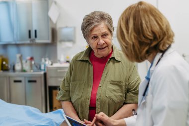 Geriatrist, muayene sırasında yaşlı bir hastayla test sonuçları hakkında konuşuyor. Tıbbi danışma.