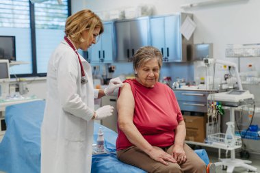 Yaşlı hasta doktor tarafından aşılanıyor. Koruyucu bakım.