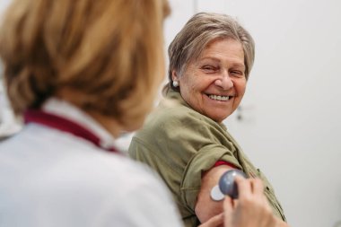Yaşlı hastaların koluna CGM sensörü takan kadın doktor. Tıbbi ayar.